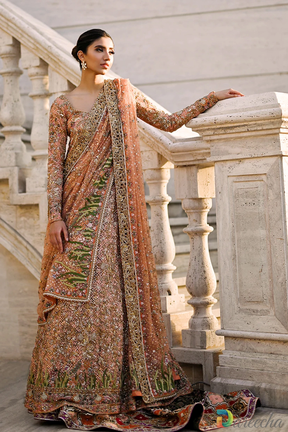 Full length view of model standing on stone staircase wearing coral tulle bridal peshwaslehenga border and burnt tangerine jamawar shawl draped across body