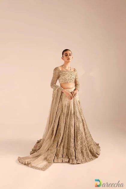 Standing view of model inchampagne kundan bridal lehengaholding draped mukesh work dupatta with pearl edging