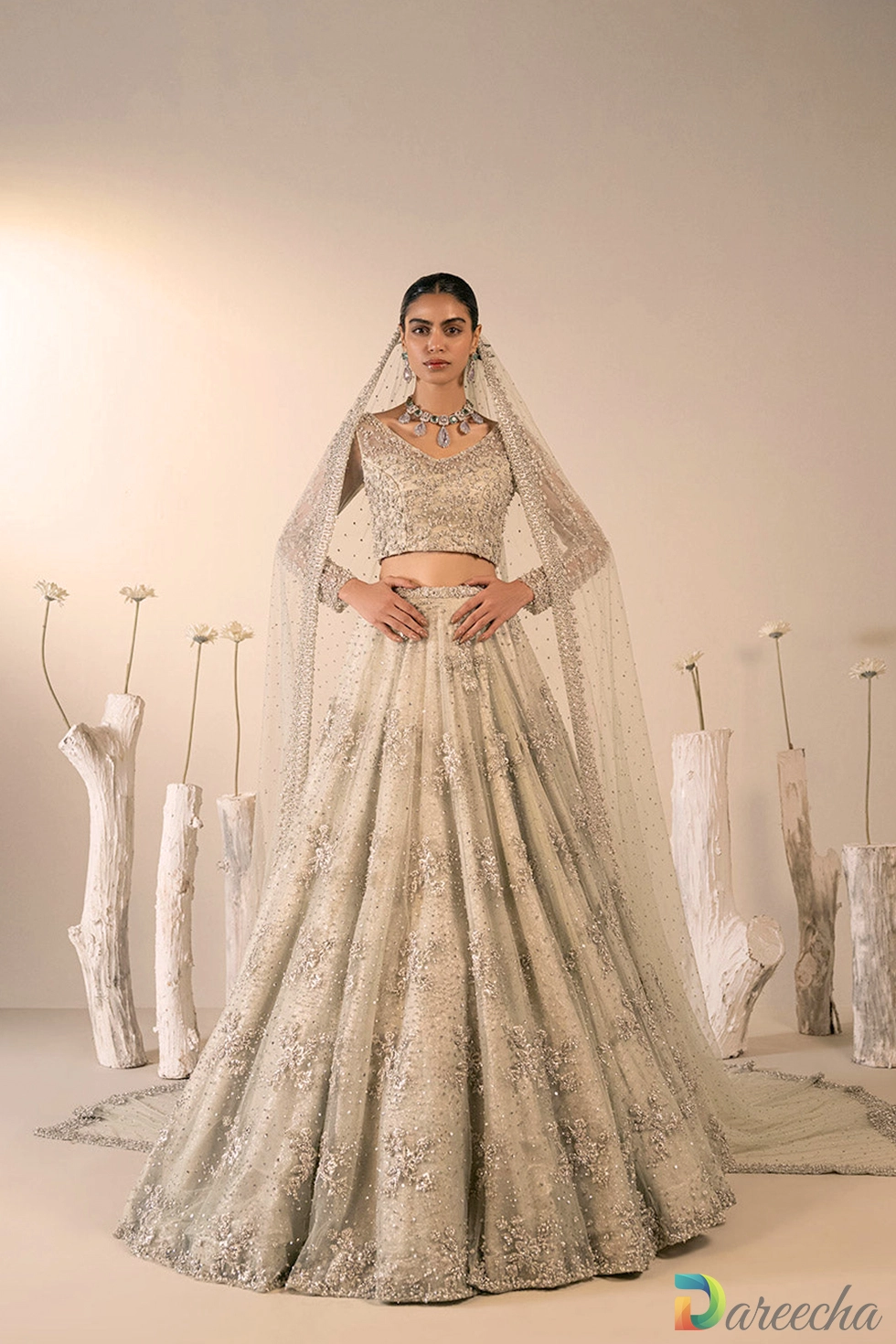 Front view of model wearing mint green bridal lehenga choli with silver zardozi embroidery and trailing embellished veil