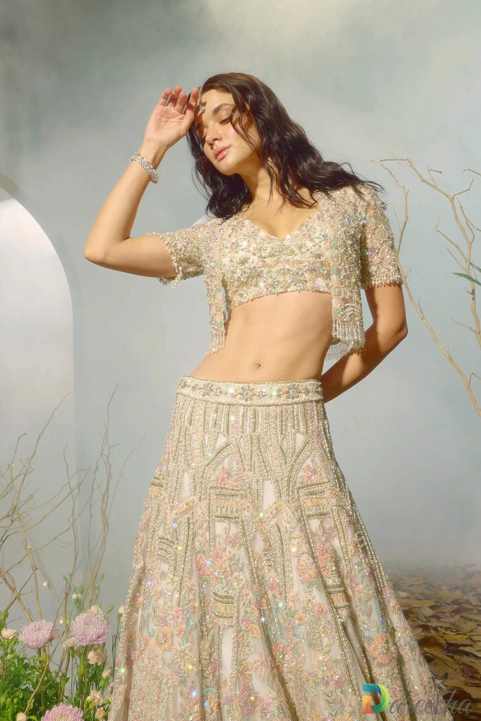 Front view of model wearing white lehenga jacket set with crystal embellished razor back jacket and crop top choli