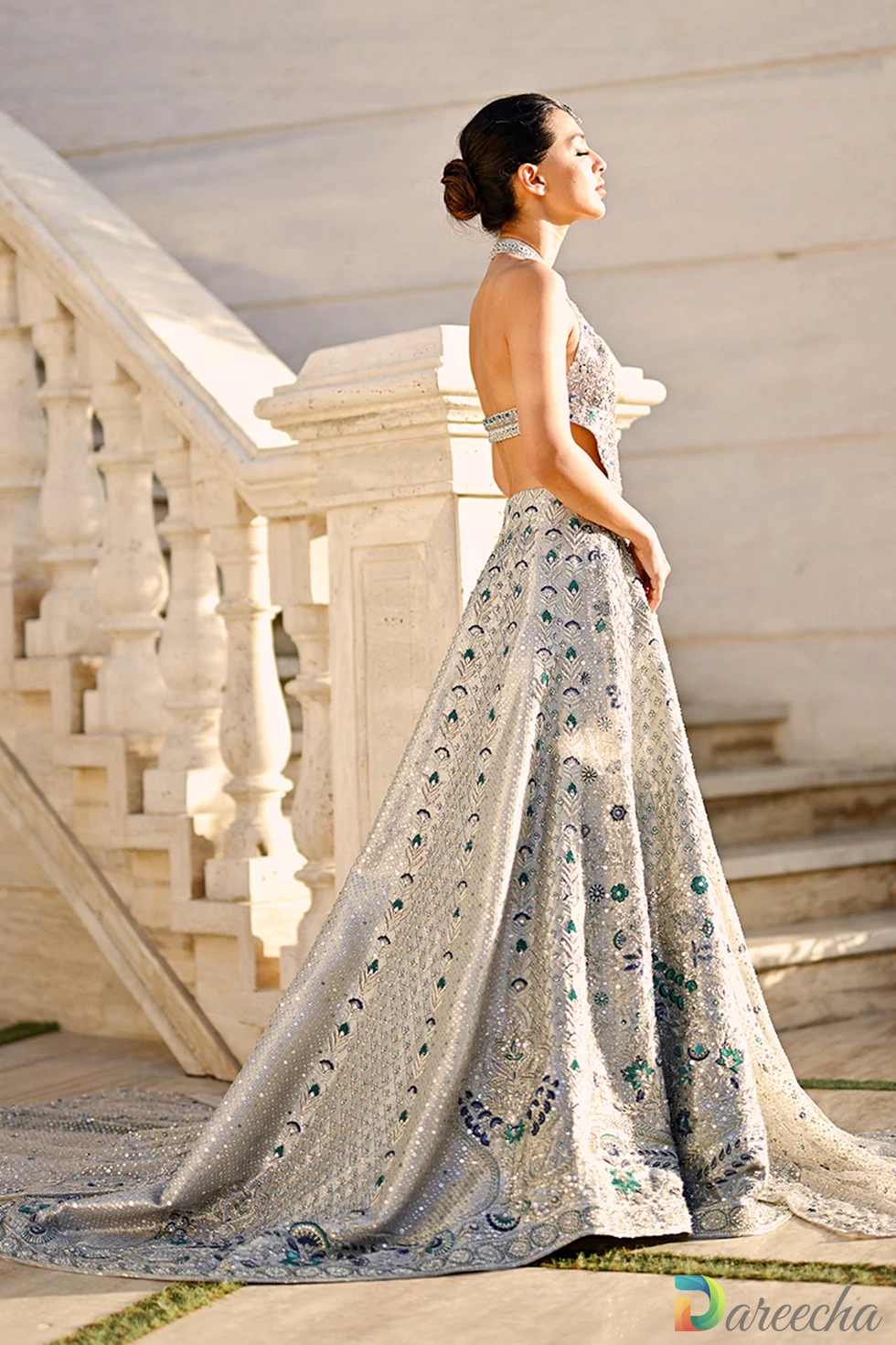 Model in an icy platinum backless bridal peshwas with geometric zardoze embroidery and halter back cutout.