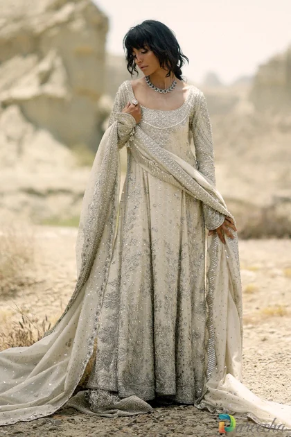 Full length front view of model wearing ivory peshwas with dhaka pajama showing scoop neckline pearl cuff tassels and cutwork lattice hem[cite: 27]
