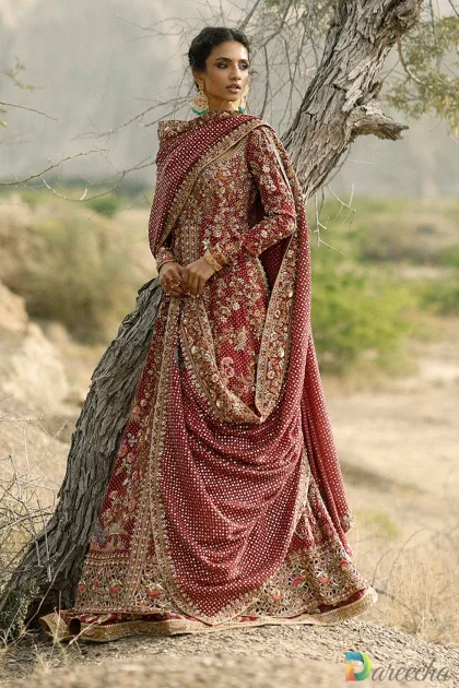 Front view of model wearing crimson peshwas bridal lehenga showcasing Queen Anne neckline and full sleeves[cite: 35]