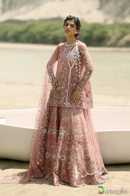 Standing profile in grass showing tissue tube top and flared skirt of pink tulle angrakha lehenga