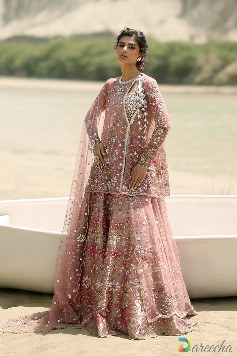 Standing profile in grass showing tissue tube top and flared skirt of pink tulle angrakha lehenga