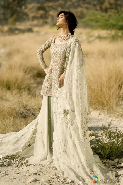 Full length standing portrait in desert setting of celadon tulle short shirt lehenga with draped veil