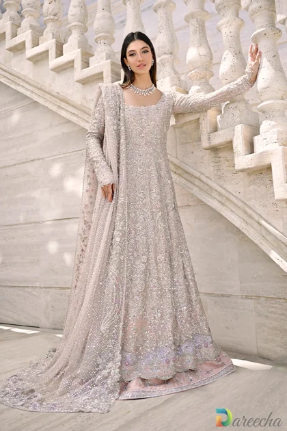 Full length front view of model on marble staircase wearing champagne pink peshwas lehenga with silver zardoze embroidery and draped tulle dupatta
