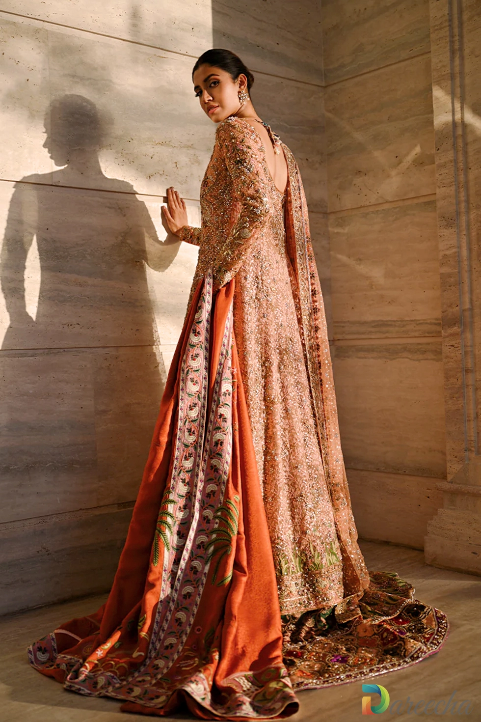 Back three quarter view of model displaying sheer coral tulle back design with sweeping burnt tangerine jamawar shawl featuring palm motifs[cite: 20]