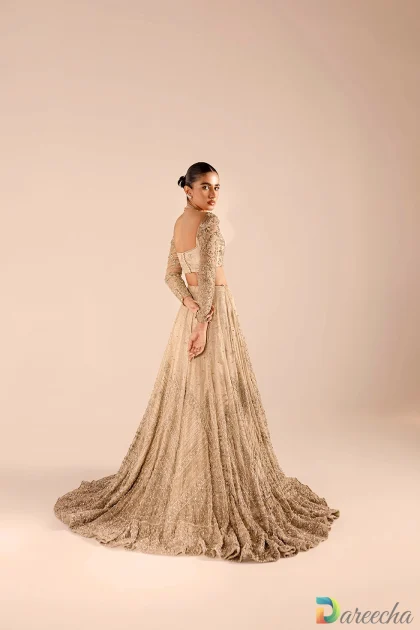 Back view of model wearing champagne embellished lehenga choli with sweeping lehenga train