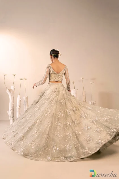 Back three quarter twirling view showing deep V back net choli and sweeping flared mint green lehenga