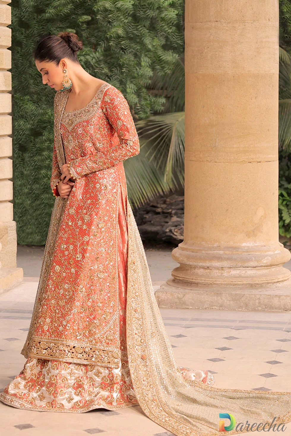 Side view of model wearing coral tissue A line long shirt lehenga showing long sleeves and detailed cutwork hem