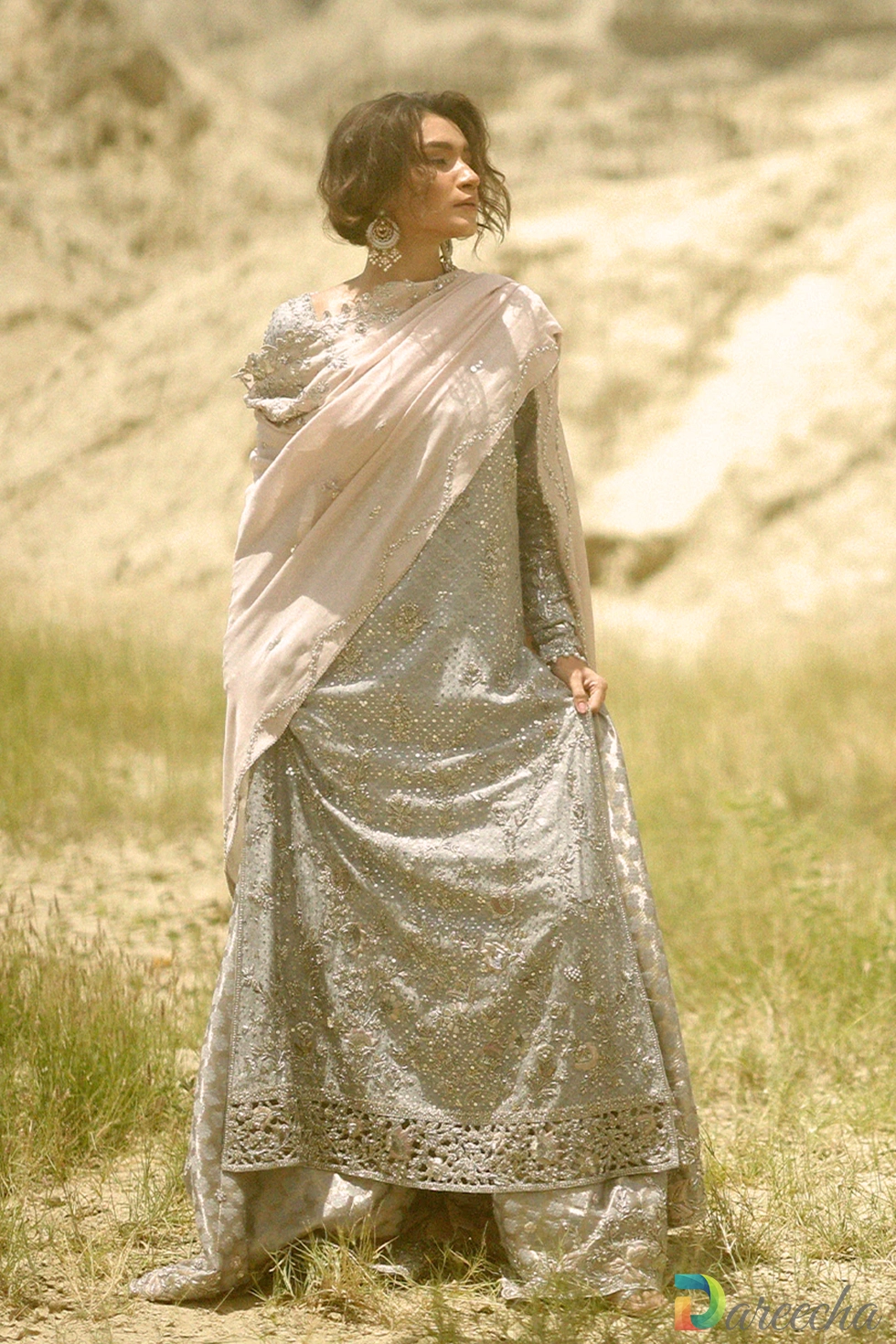 Front angle view showing draped blush dupatta and cutwork hem of steel blue long shirt with lehenga