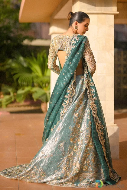 Back profile of model in mint green tissue peshwas displaying cutwork sleeves and emerald organza dupatta
