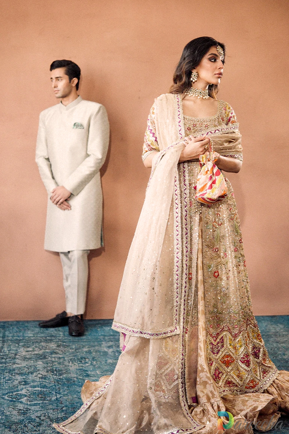 South Asian bride in embellished gold and copper peshwas paired with groom in beige sherwani
