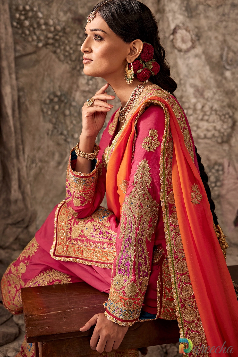 Close up portrait of model wearing fuchsia pink silk kurta with gold tilla embroidery, blue neckline placket accent, and statement bridal jewelry