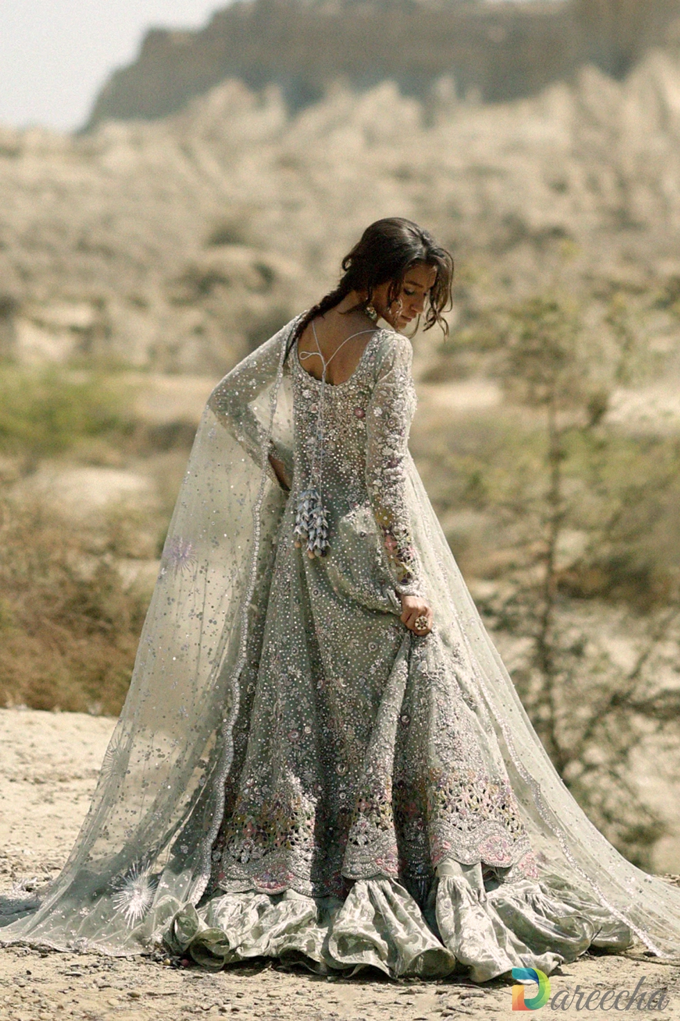 Back view of model wearing frosted mint peshwas lehenga showing backless scoop neckline with three dimensional tassels and sweeping tulle dupatta train[cite: 24]