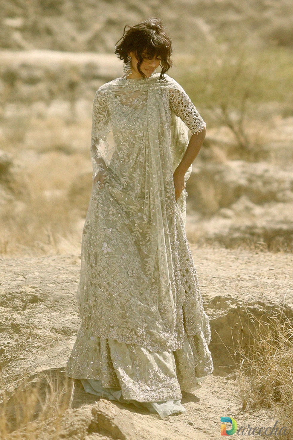 Full length standing pose in outdoor landscape showing mint green tissue peshwas lehenga and draped dupatta