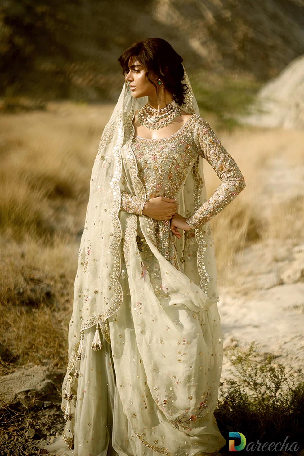 Close up profile of celadon tulle short shirt lehenga displaying chinoiserie crane and pagoda zardoze embroidery