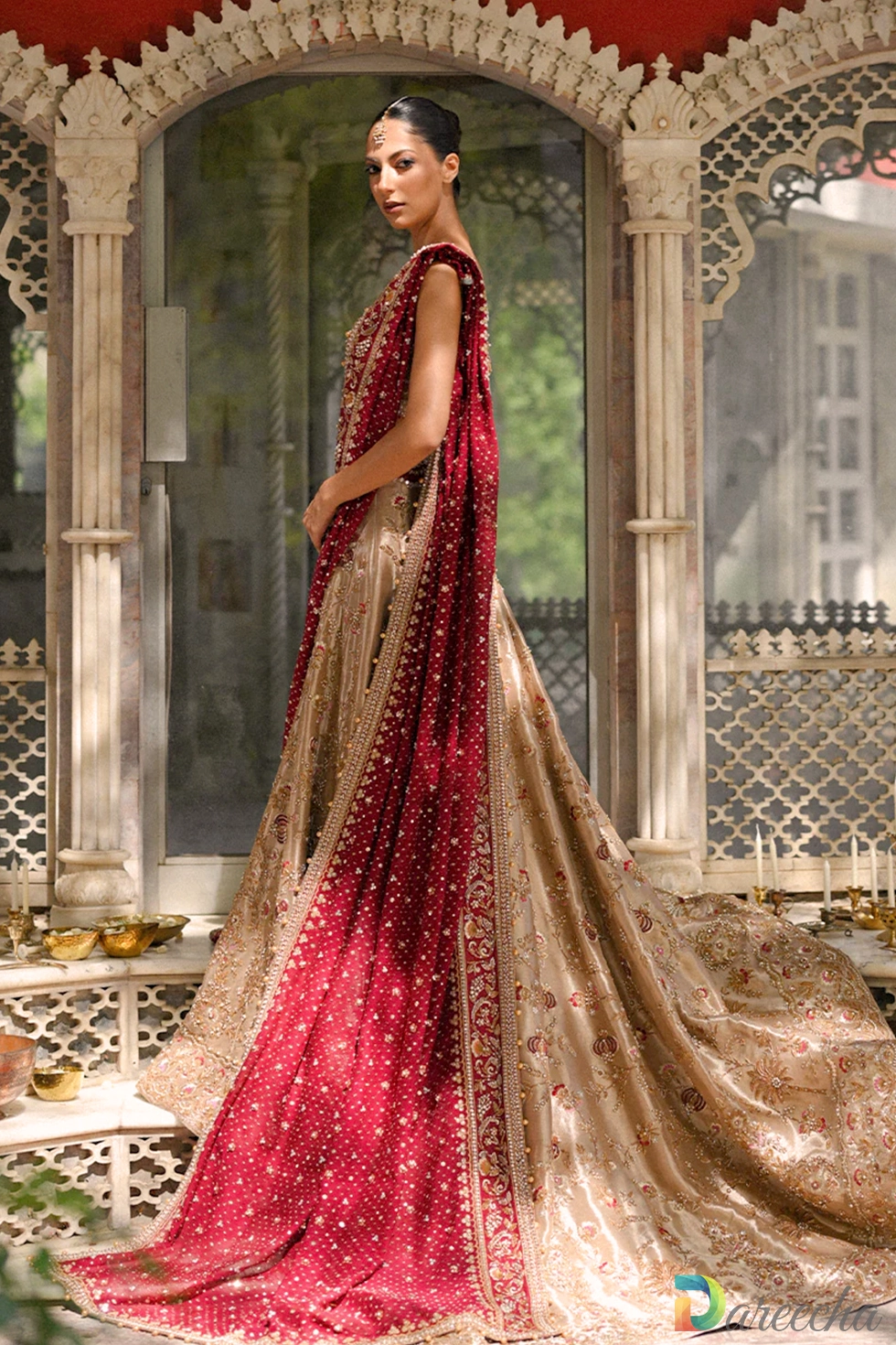Side profile view of model in gold tissue lehenga choli displaying flared skirt train and draped red dupatta[cite: 20, 22]