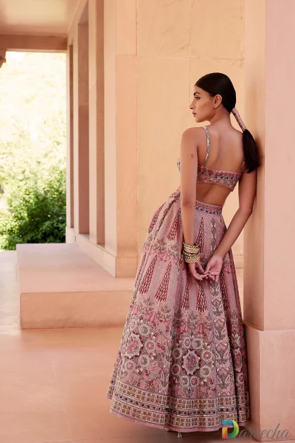 Three quarter back view showing model in dusty rose embroidered matka silk bustier top and flared skirt