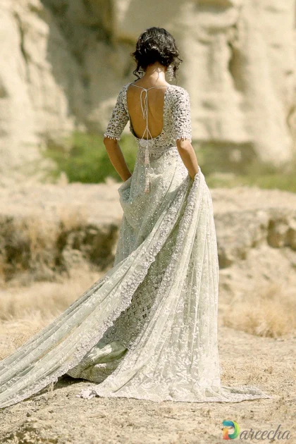 Back view of model wearing mint green tissue peshwas lehenga with deep scoop back tie and pearl tassels
