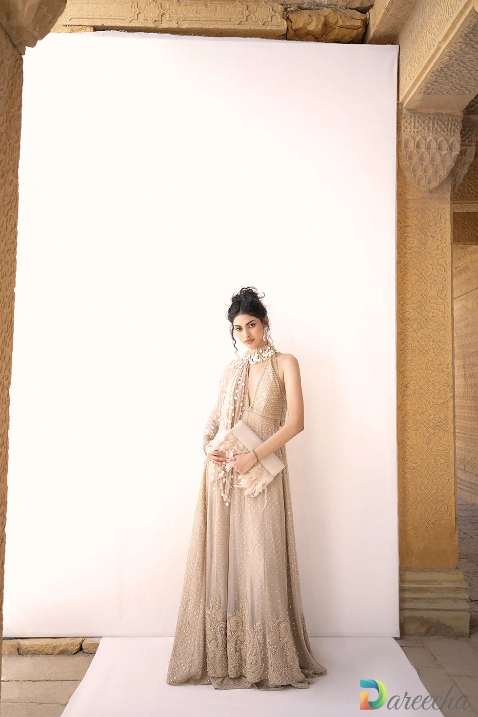 Front view standing between stone arches showcasing coin neck drape and beige crinkle chiffon lehenga