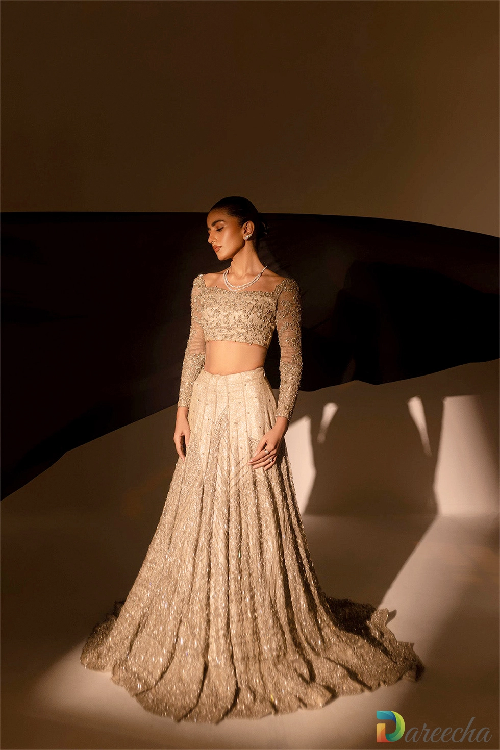 Dramatic studio portrait of model wearing champagne kundan net bridal outfit with warm studio lighting
