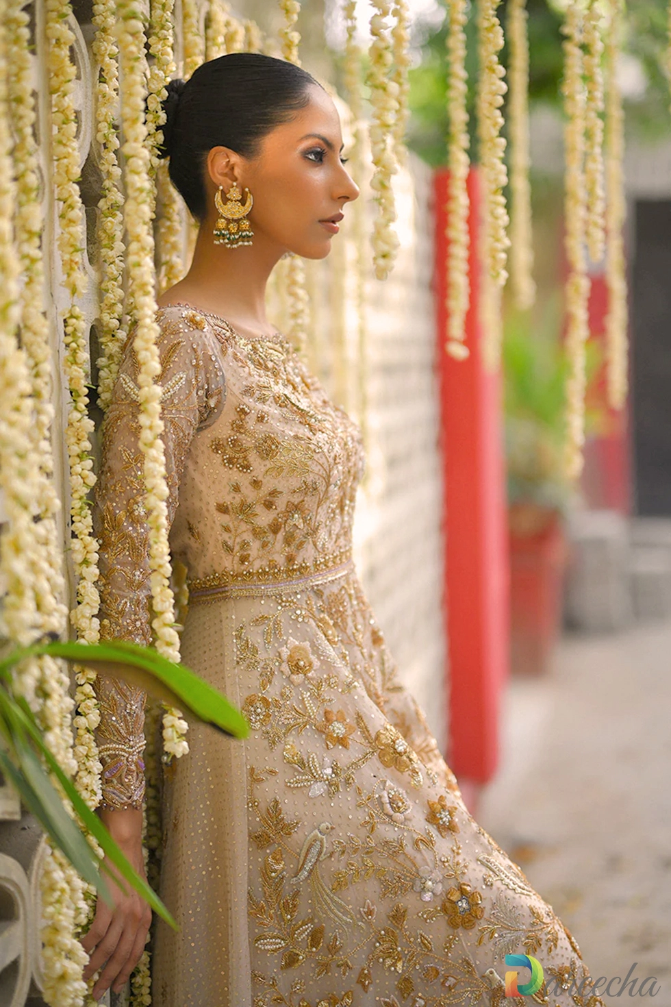Side profile against floral backdrop showing long sleeve embroidery on pale pink tulle peshwas lehenga