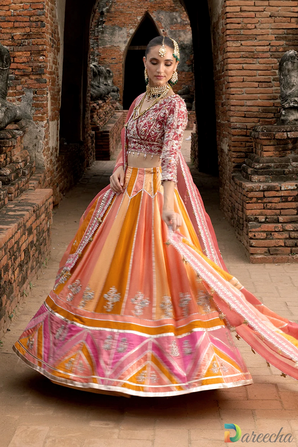 Standing portrait of model in multi color chatta pati lehenga with draped sheer organza dupatta