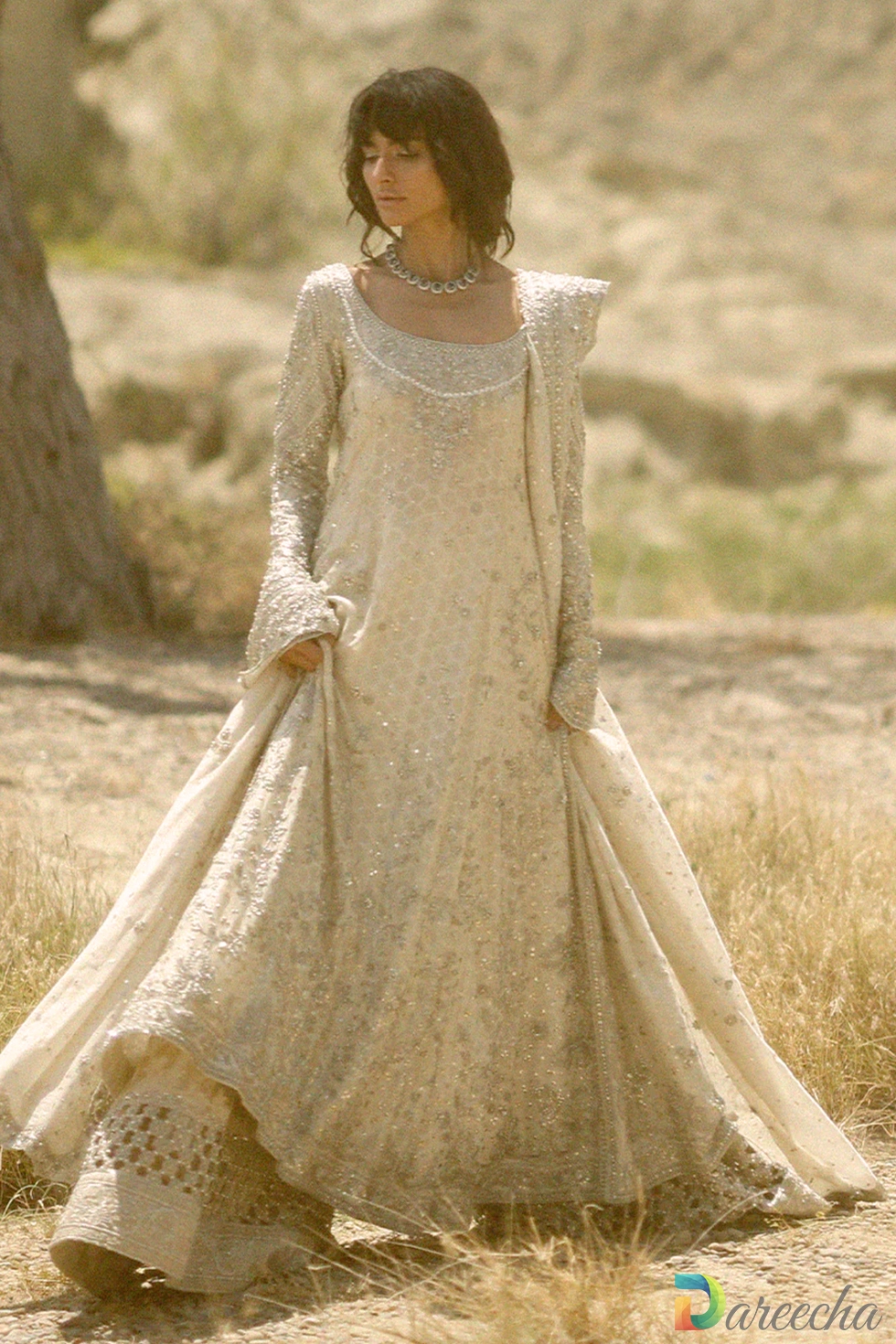 Side profile view of model wearing ivory peshwas with dhaka pajama showing deep back neck detailing and flared tissue brocade hem[cite: