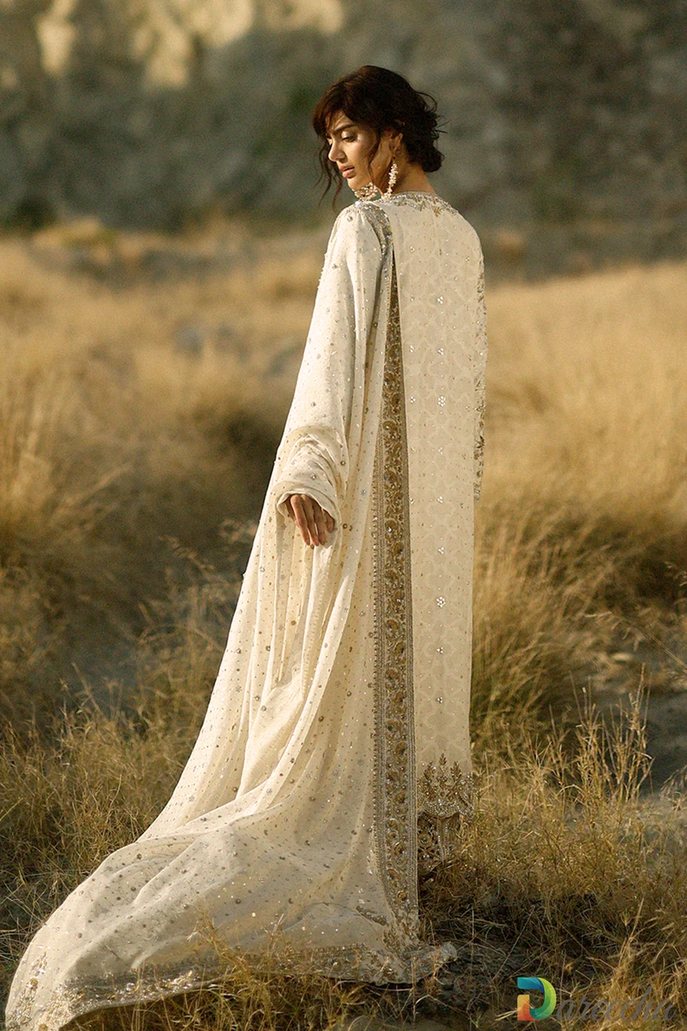 Rear profile view of model wearing the ivory hand embroidered long shirt showing the flowing cotton net dupatta with zardoze borders
