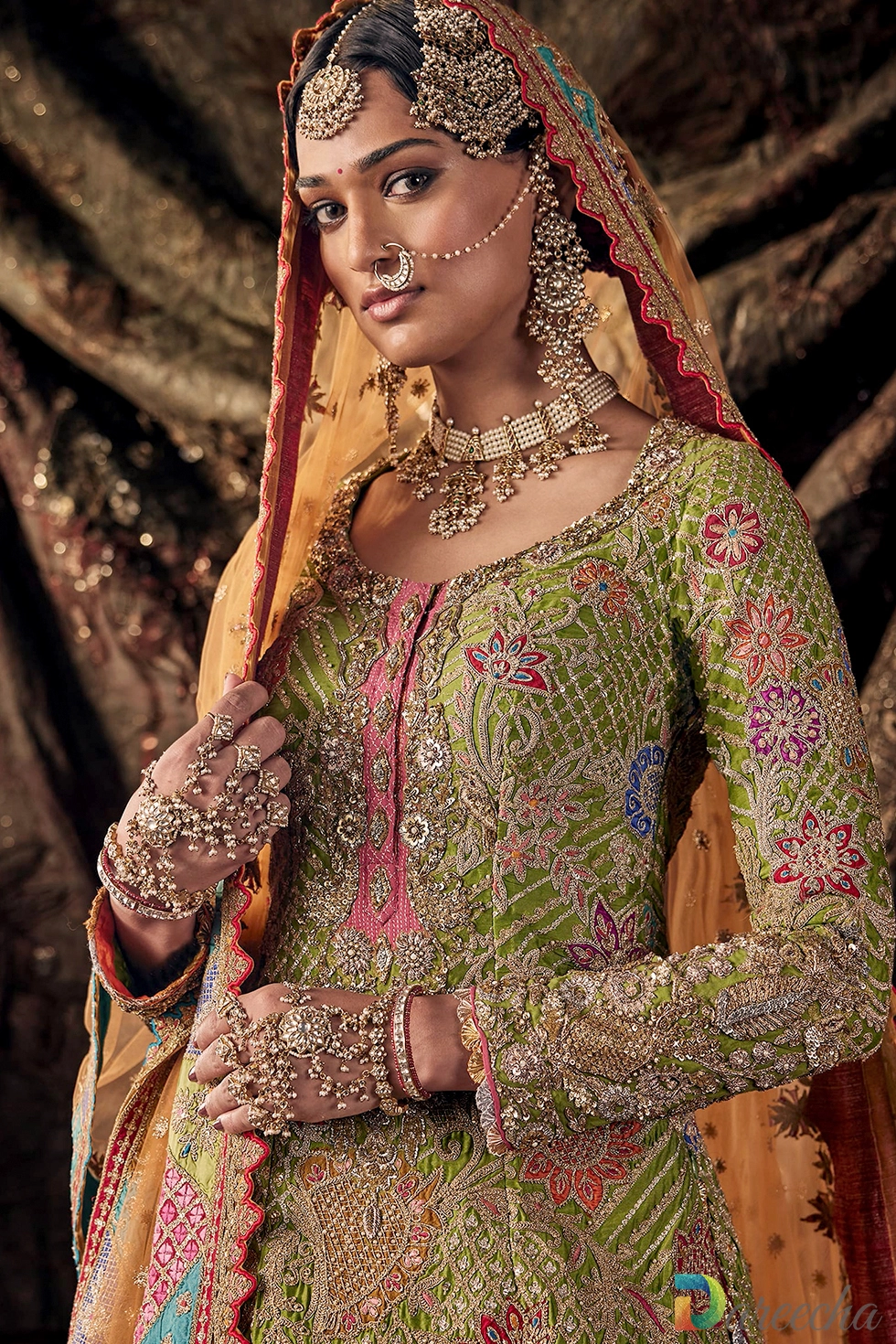 Close up view of model wearing parakeet green kurti with pink placket and rust orange odhna displaying pearl jewelry and tikka