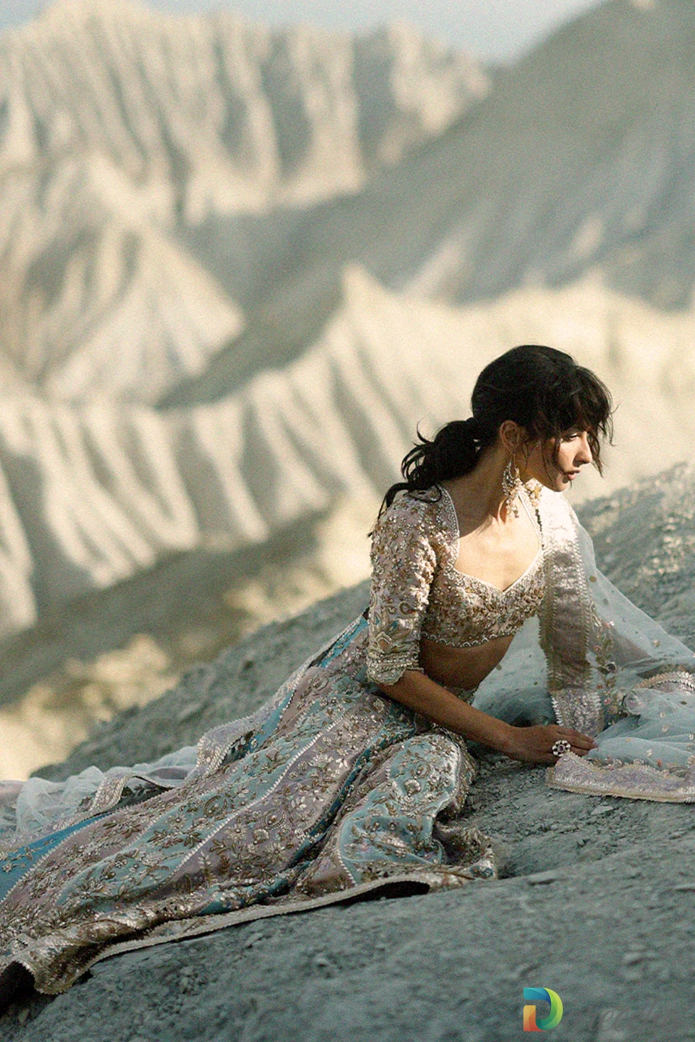 Model leaning against rock backdrop showing side profile of blush tissue choli and celadon panelled lehenga