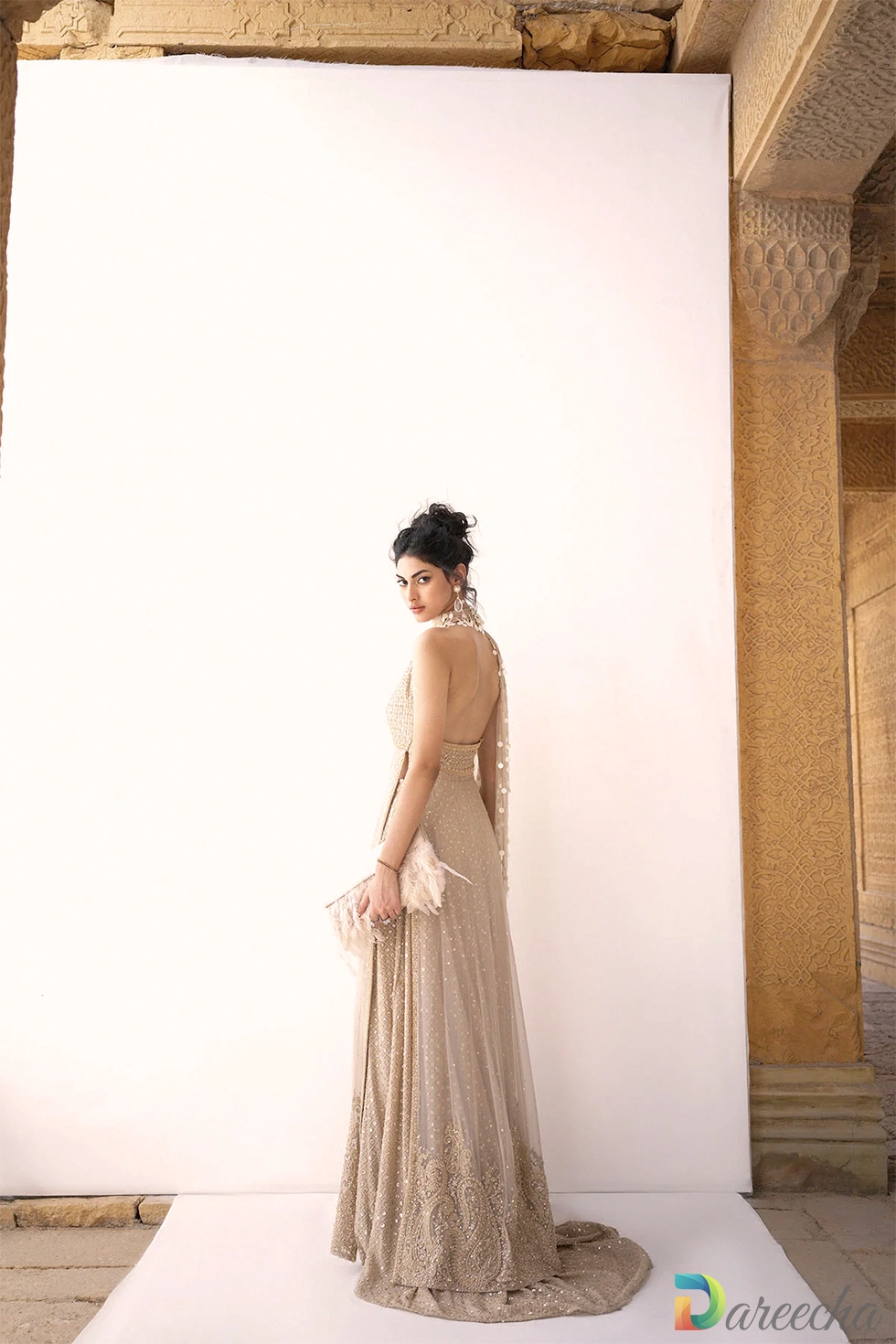 Side back profile showing halter back cut and trailing skirt hem on beige crinkle chiffon lehenga