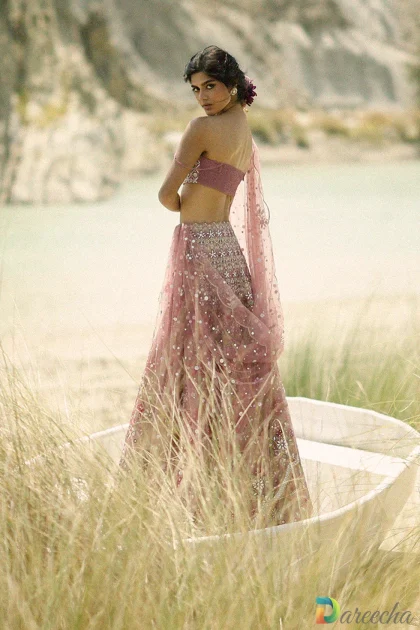 Back side profile of model in boat wearing pink tulle angrakha lehenga with strapless tissue tube top