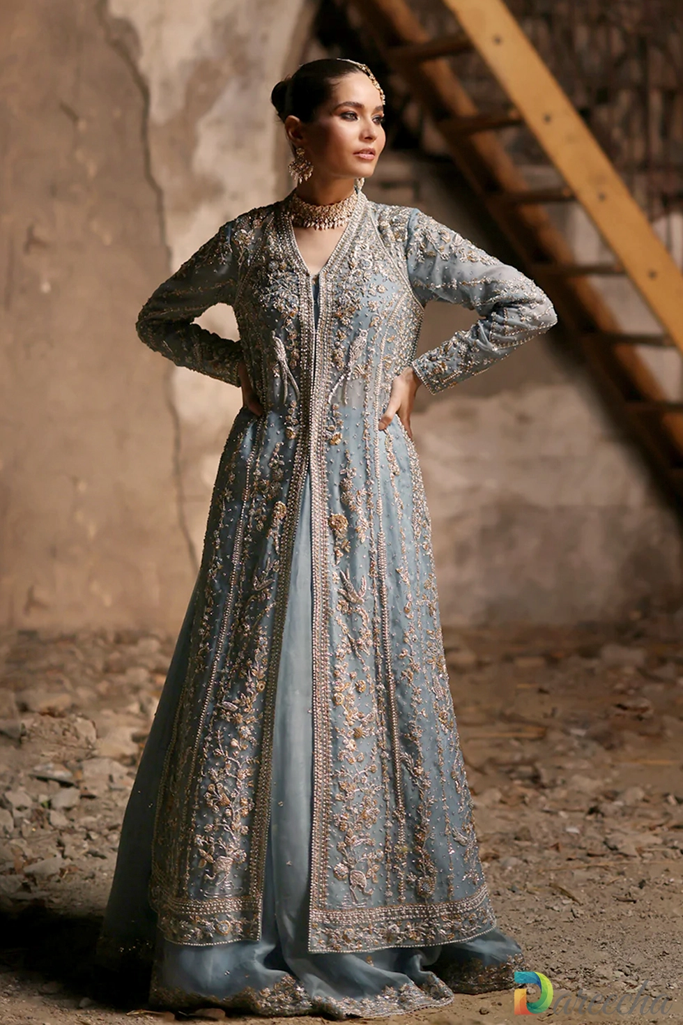 Full length standing portrait displaying powder blue front open lehenga jacket and flowing organza skirt