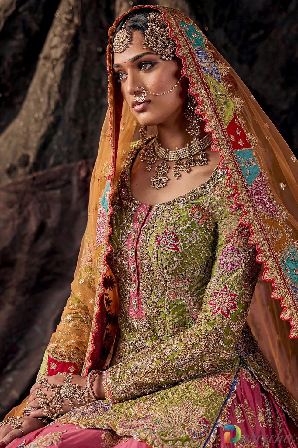 Close up view of model wearing parakeet green kurti with pink placket and rust orange odhna displaying pearl jewelry and tikka