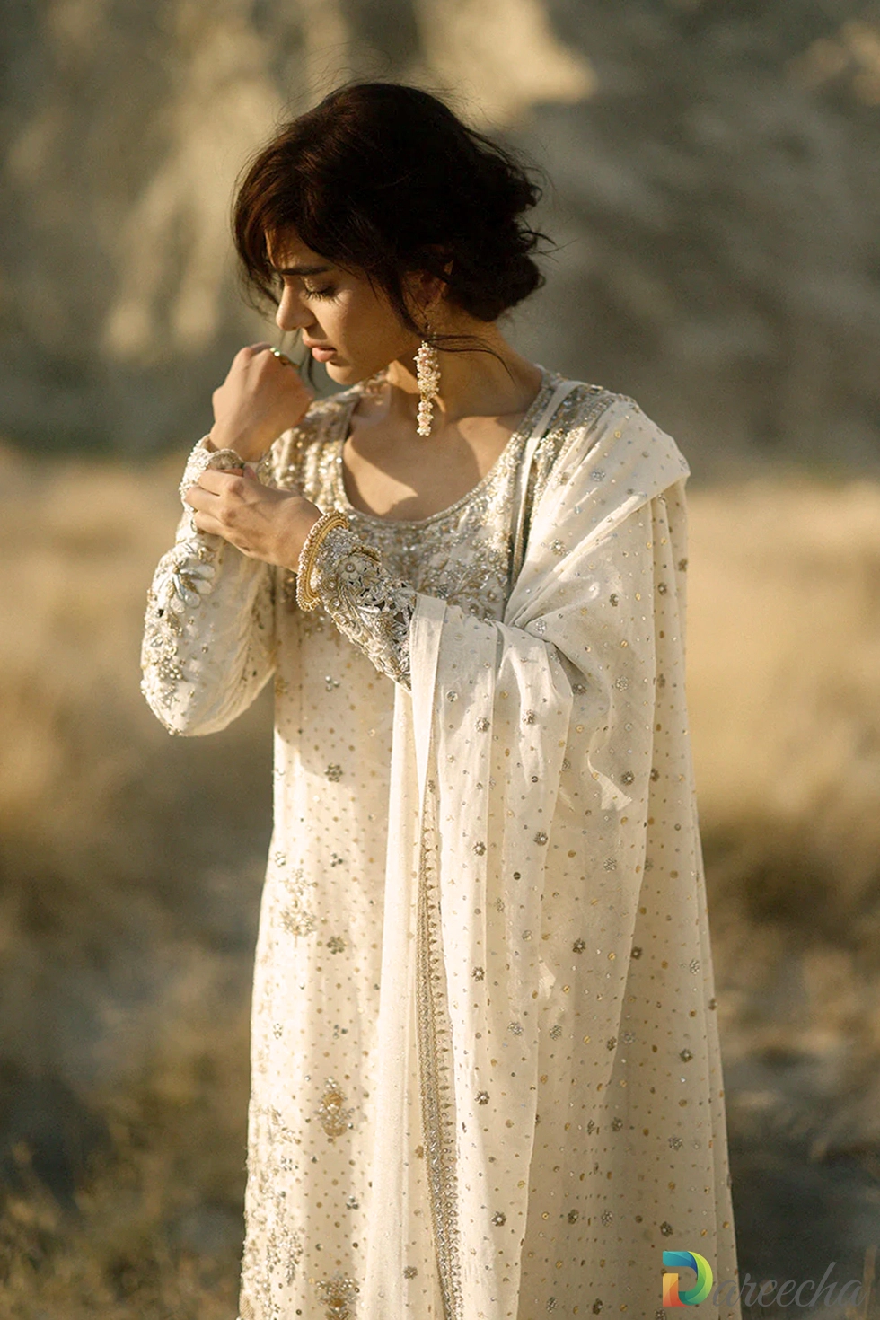 Close up view of model in the ivory hand embroidered long shirt detailing the round zardoze neckline and sleeve cuff embroidery
