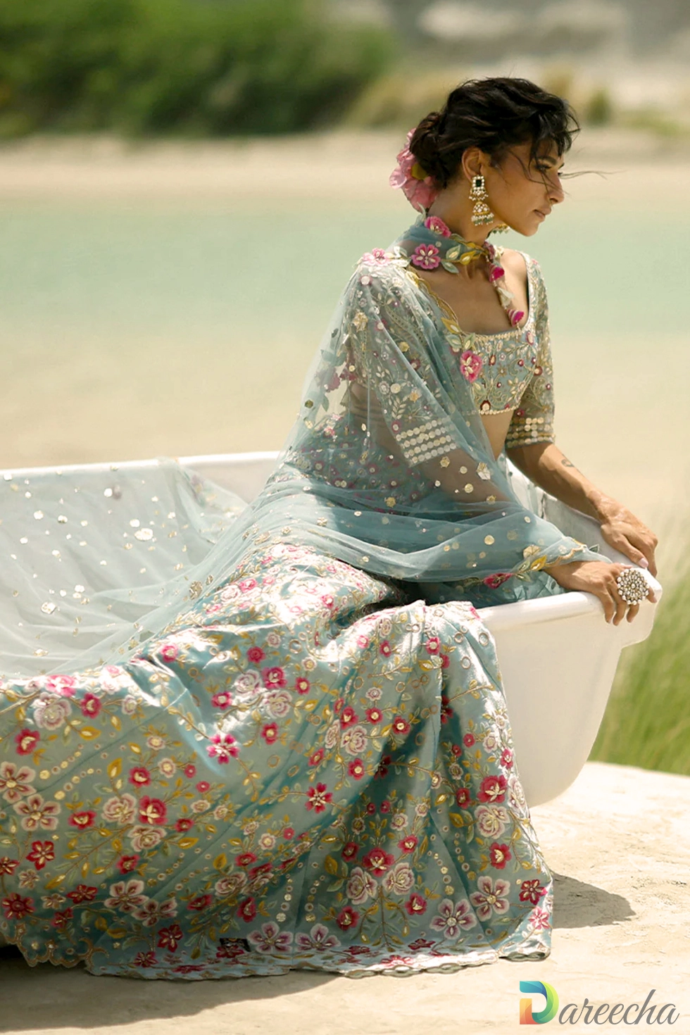 Seated portrait showing ice blue tissue lehenga with embroidered short sleeves and draped tulle dupatta