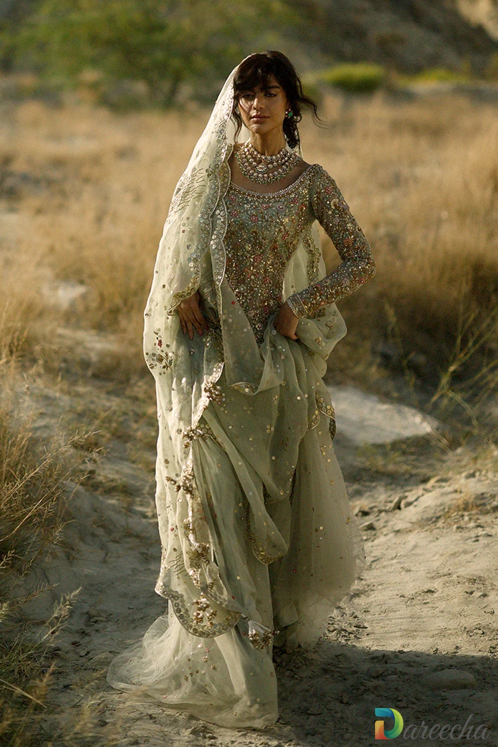 Three quarter pose of celadon tulle short shirt lehenga showing pearl tassels and scalloped zardoze dupatta border