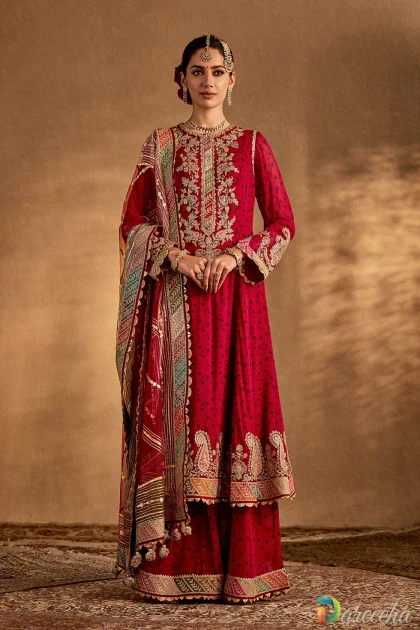 Model wearing an earthy maroon embroidered sharara suit with gold marodi ka kaam on the neckline and an organza dupatta.