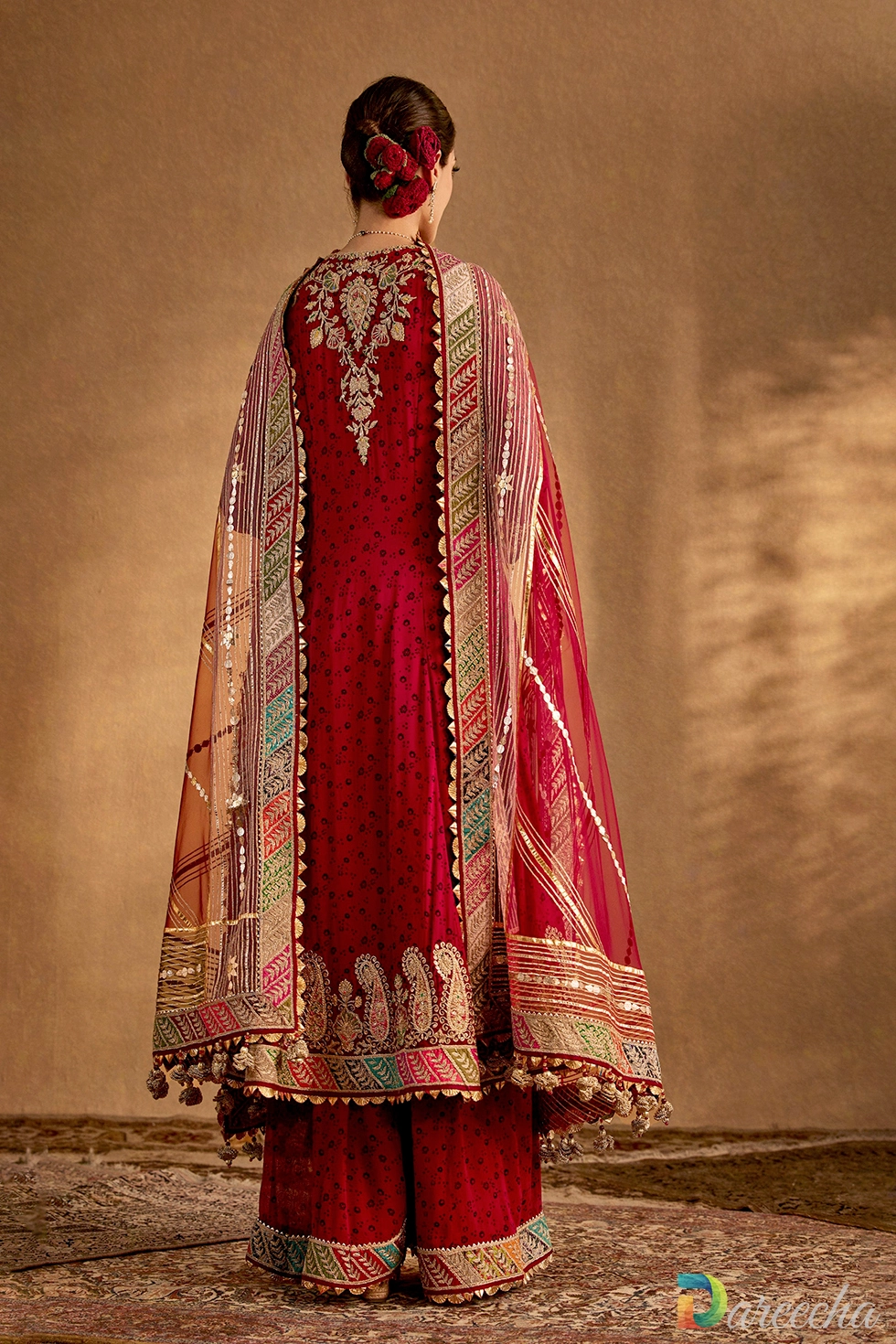 Back view of a deep maroon printed silk kurta set showcasing hand-embroidered back motifs and draped organza dupatta.