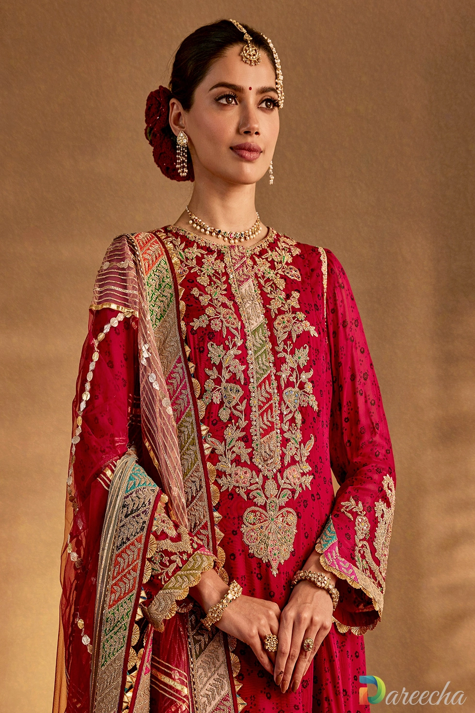 Close-up of rich marodi embroidery, pearls, zardozi work, and chevron borders on a maroon silk kurta hem.
