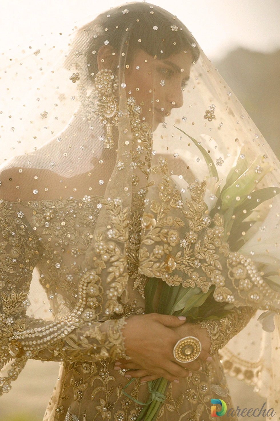 Close-up of off-shoulder zardoze embroidery and pearl clusters on sheer gold tulle.