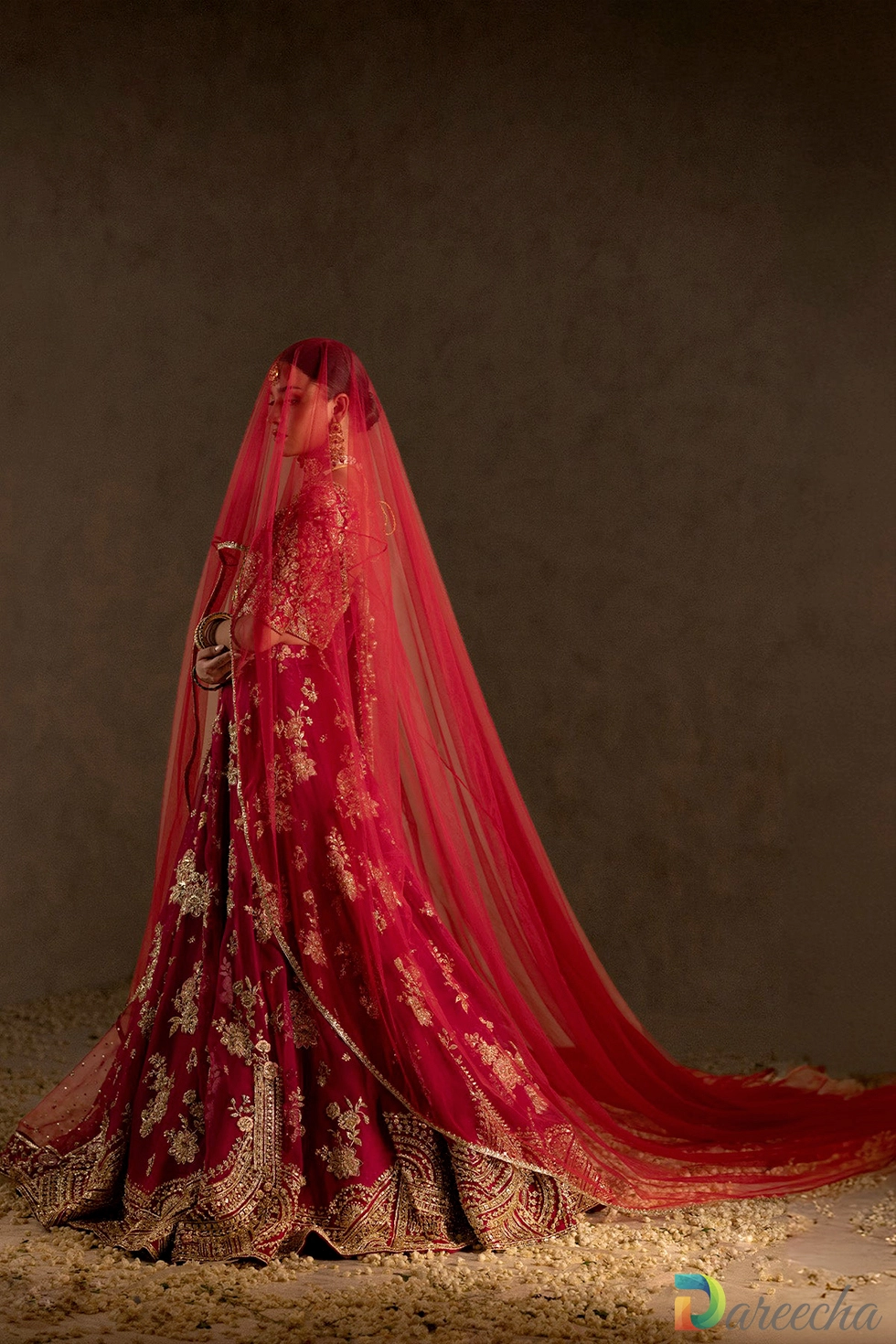 Red bridal veil draped over embroidered gown
